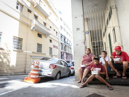 Maxwell Oliveira e Verônica Medeiros almoçam, junto com seus dois filhos, após receber doação de marmita de uma ONG, em São Paulo.