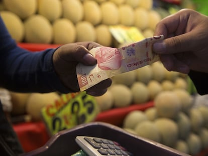 Un comprador paga fruta con un billete de 100 pesos en un puesto de la Central de Abastos de Ciudad de México.