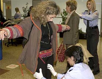 Dos vigilantes del aeropuerto de Barajas (Madrid) cachean a dos pasajeras.