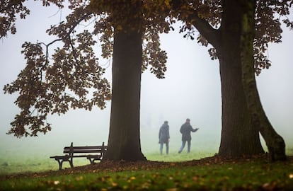 Personas paseando bajo la niebla por un parque de Frankfurt, Alemania.