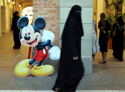 Una mujer cubierta con el tradicional chador musulmán pasa ante una silueta de Mickey Mouse en un centro comercial de Dubai.