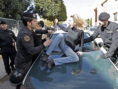 Isabel Monr&oacute;s jumps on a Civil Guard vehicle as she tries to prevent her former husband from leaving with her children.