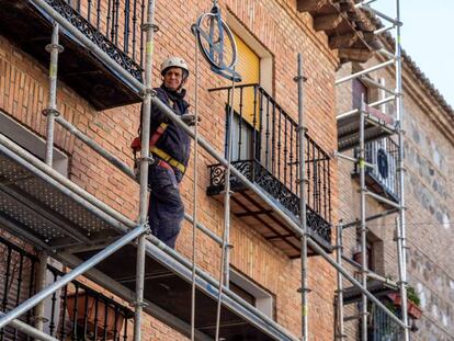 Un obrero de la construcción trabaja sobre un andamio en una calle en Toledo.