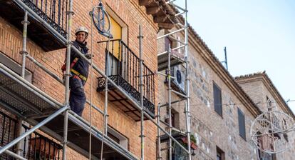 Un obrero de la construcción trabaja sobre un andamio en una calle en Toledo.