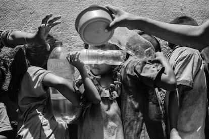 Niños venezolanos hacen cola para rellenar sus botellas de agua y recibir comida de una organización humanitaria en la localidad de Paraguachón, Colombia.