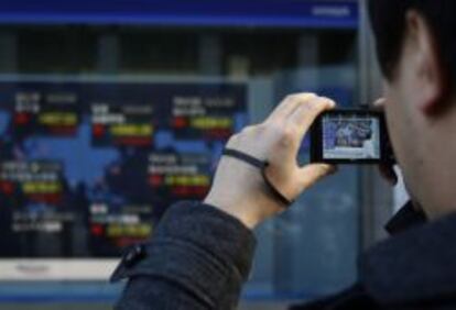 Un caminante hace una foto a un panel de cotizaciones en Tokio