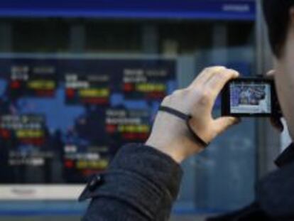 Un caminante hace una foto a un panel de cotizaciones en Tokio