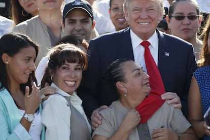 Una empleada del candidato republicano Donald Trump agarra su corbata mientras posan para los medios gráficos durante un evento en el Trump National Dora, en Miami el 25 de octubre de 2016.