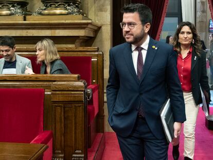 El 'president' Pere Aragonés (centro), acompañado por la consejera de Presidencia, Laura Vilagrá (der.) pasan al lado de la bancada de En Comú Podem en el Parlament.