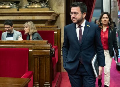 El 'president' Pere Aragonés (centro), acompañado por la consejera de Presidencia, Laura Vilagrá (der.) pasan al lado de la bancada de En Comú Podem en el Parlament.
