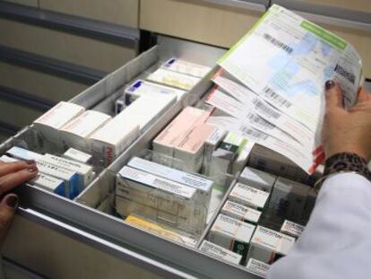 Una farmacéutica busca un medicamento con receta.