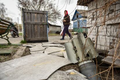 Una mujer camina junto a una parte de un misil en el patio de una casa privada en la aldea de Kukhari, en la zona de Kiev, Ucrania, el pasado martes. 