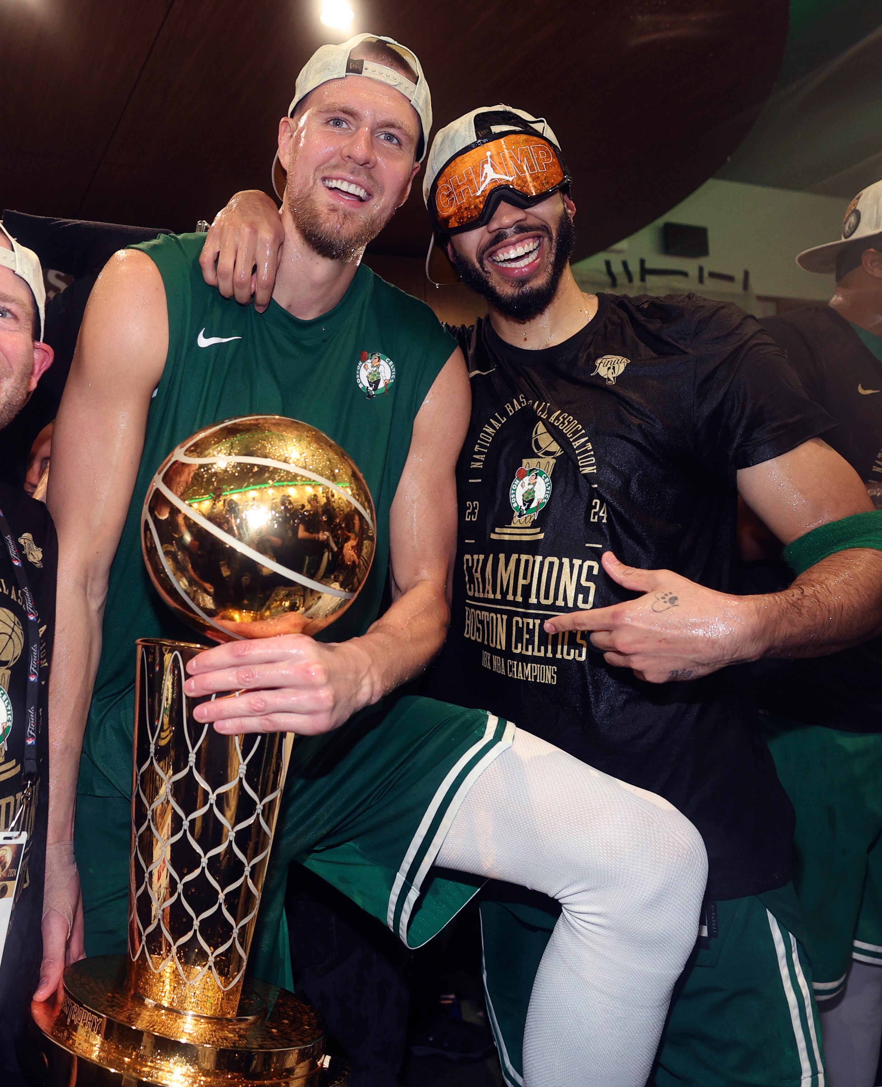 Kristaps Porzingis, a la izquierda, sostiene el trofeo junto a su compañero de equipo Larry O'Brien.