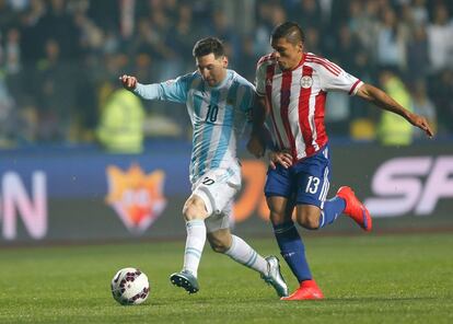 Messi lucha por defender el balón del paraguayo Ortiz.
