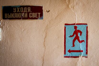 A sign asking people to turn off the light when leaving, next to another marking the emergency exit to the shelter in case of shelling, at a center for internally displaced persons in Kharkiv, August 2, 2024.