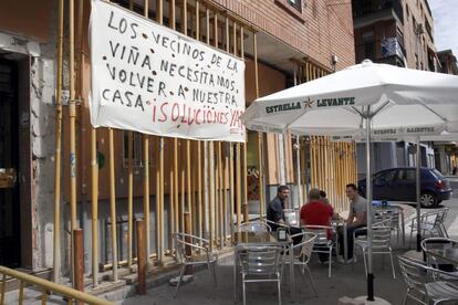 Una terraza, a las puertas de un edificio con andamios para reforzar la estructura.