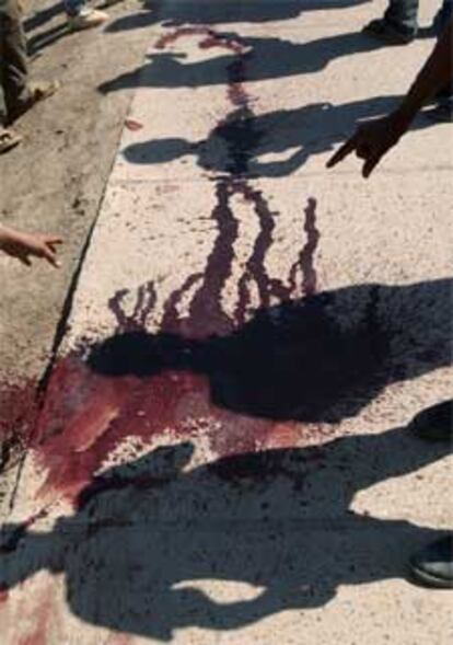 Un grupo de iraquíes contempla restos de sangre donde tropas de EE UU han sido atacadas por insurgentes en Bagdad.