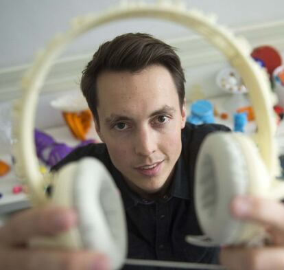 Un hombre muestra unos auriculares realizados por una impresora 3D.