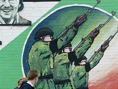 Una familia pasa delante de un mural del IRA en Belfast, en julio de 2002.