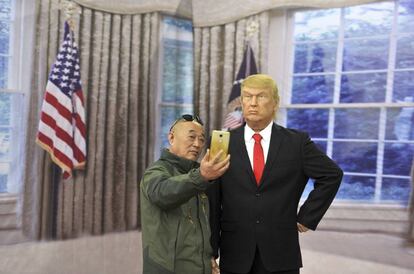 Un hombre se toma una fotografía junto a una figura de cera del presidente Trump.