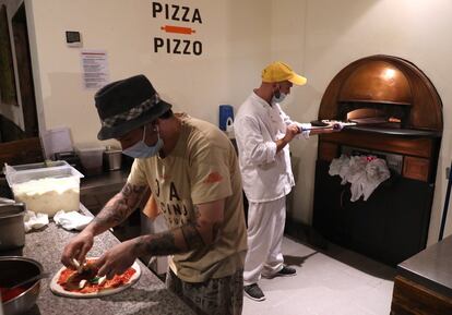 Unos beneficiarios del proyecto de inclusión social y laboral para discapacitados de la pizzería Porta Pazienza, situada en Pilastro, el suburbio más desfavorecido de Bolonia, preparan la pizza. Este restaurante aboga por implantar una "ética del consumo" que incluye la exclusividad dada a los alimentos ecológicos, no solo de productores locales, sino también los que se cultivan en terrenos confiscados a la mafia en el sur de Italia.