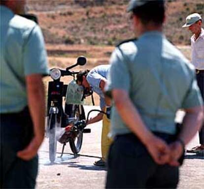 Agentes de la Guardia civil, ayer, vigilaban la desinfectación de una moto que salía de la zona de Alpuente