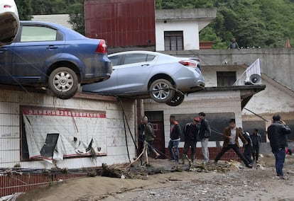 Residentes de Yudong (China) intentan retirar los coches atrapados en lo alto de un edificio, tras ser arrastrados por las fuertes lluvias que golpearon el municipio.