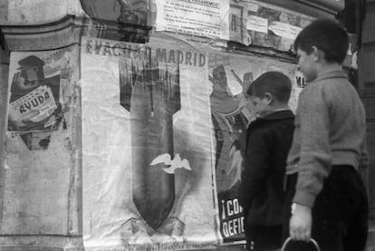 Un niño observa un cartel que aconseja a la población evacuar la ciudad para evitar los bombardeos nacionales, en Madrid, el 20 de enero de 1937.
