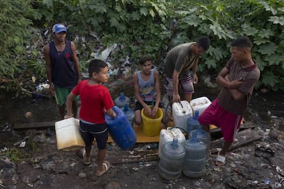 Un grupo de jóvenes se abastece de agua en un riachuelo formado por una tubería rota, el pasado viernes en Maracaibo.