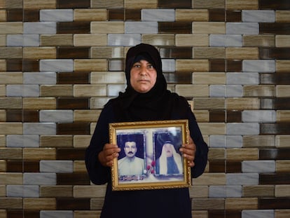 Um Omar sostiene un cuadro con las fotografías de su marido Muntadar (izquierda), desaparecido en 2016, y de su padre fallecido.