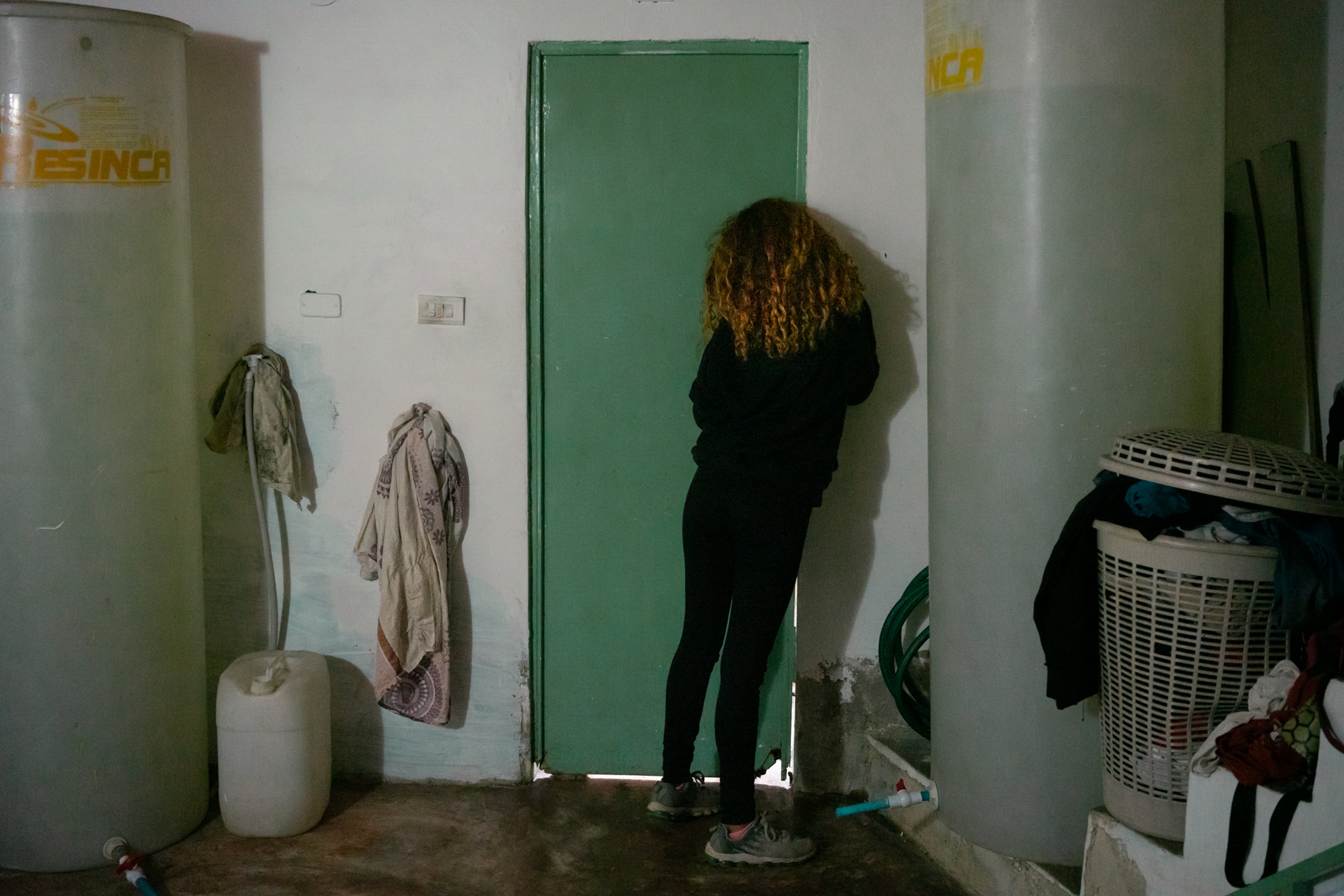 Una acompañante le pregunta a la mujer que está pasando por el proceso del aborto si puede entrar al baño para sostenerle el cabello y el cuerpo mientras vomita y se sienta en el inodoro, en una casa situada en una zona popular de Caracas, Venezuela, el 25 de agosto de 2022. Cerca de esta vivienda, las fuerzas policiales detienen a todas las personas que entran al barrio en un puesto de control improvisado.