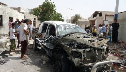 Ciudadanos observan el estado en que ha quedado el coche después del atentado suicida del lunes.