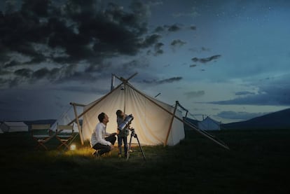 Un padre y su hijo observan el firmamento a través de un telescopio.