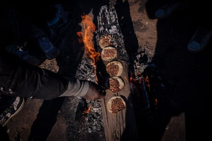 Migrantes calientan tostadas de maz sobre un tronco que alimenta la fogata encendida dentro de un vagn del tren, el 11 de enero de 2025. 