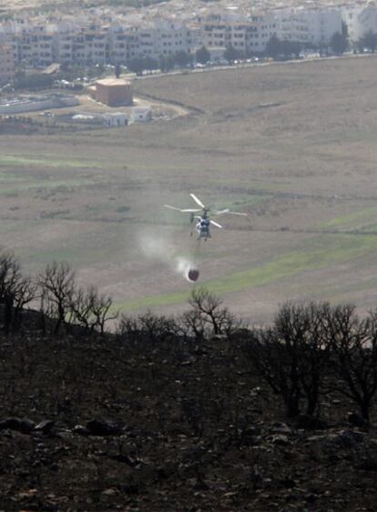 Un helicóptero arroja agua en la zona del incendio.