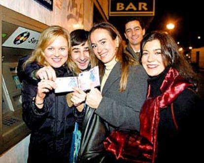 Un grupo de jóvenes muestra en Madrid sus primeros euros, obtenidos en un cajero automático.