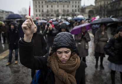 Uma mulher simbolicamente levanta uma caneta enquanto mantém um minuto de silêncio em frente à Catedral de Notre Dame, em Paris, em 8 de janeiro de 2015, em memória das doze vítimas do ataque à sede da publicação 'Charlie Hebdo'.