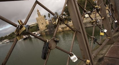 Candados en el puente de San Telmo en Sevilla. Al fondo, la Torre del Oro.