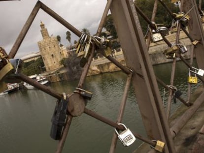 Candados en el puente de San Telmo en Sevilla. Al fondo, la Torre del Oro.