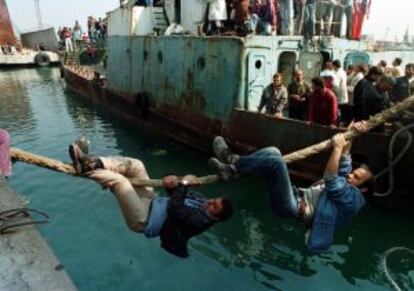 Dos hombres intentan subirse a un barco con el que huir a Italia desde el puerto de Durres (Albania), en 1997.