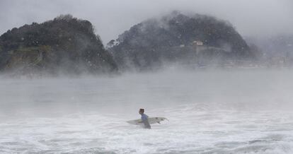 Un surfista se adentra en la playa de Ondarreta de San Sebastián (Gipuzkoa).
