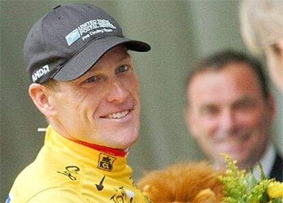 Lance Armstrong, en el podio tras enfundarse el jersey amarillo de líder y, al fondo, el pentacampeón de la ronda Bernard Hinault.