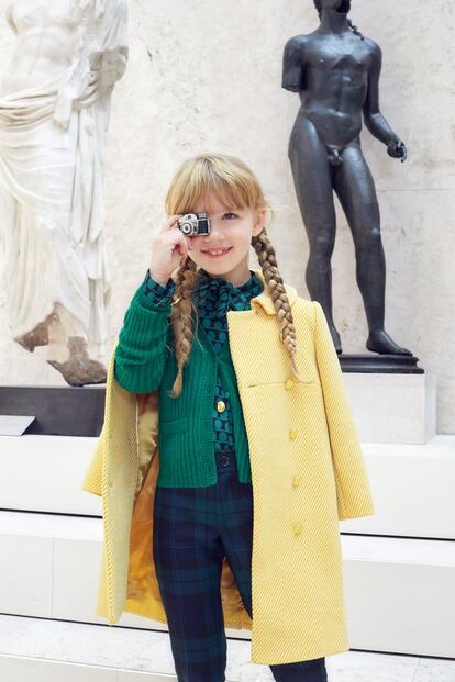 Frente a una escultura en bronce del dios Apolo en el patio romano, Estella lleva un abrigo amarillo y una camisa de lunares, ambos de Señorita Lemoniez; cárdigan 
