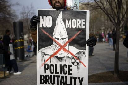 Un manifestante exhibe un cartel contra la violencia policial.