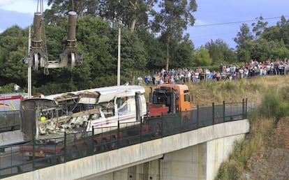 Un grupo de personas contempla hoy las labores de retirada de uno de los vagones del tren Alvia accidentado ayer en Santiago.