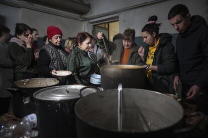 Vecinos de Mariupol hacen cola para recibir comida caliente en un refugio antibombas improvisado en Mariupol.