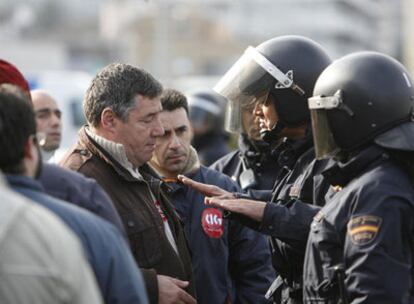 Un piquete informativo habla con un policía nacional en la entrada a la Zona Franca de Vigo, donde trataban de impedir la entrada de camiones