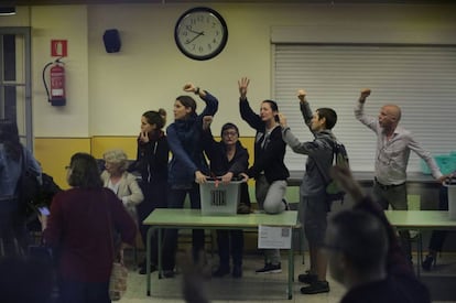 Volunteers grab a ballot box with their fists in the air at the Ramon Llull school in Barcelona.