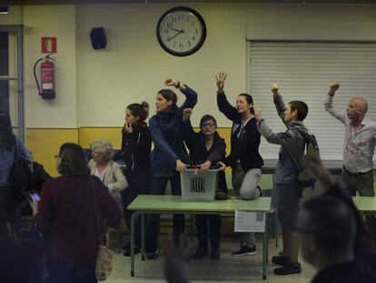 Volunteers grab a ballot box with their fists in the air at the Ramon Llull school in Barcelona.