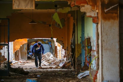 Uno de los vecinos del barrio marginal de El Raval, en Algemesí, cruza el interior de tres casas, ahora unidas después de que la dana se llevara los muros que las separaban.